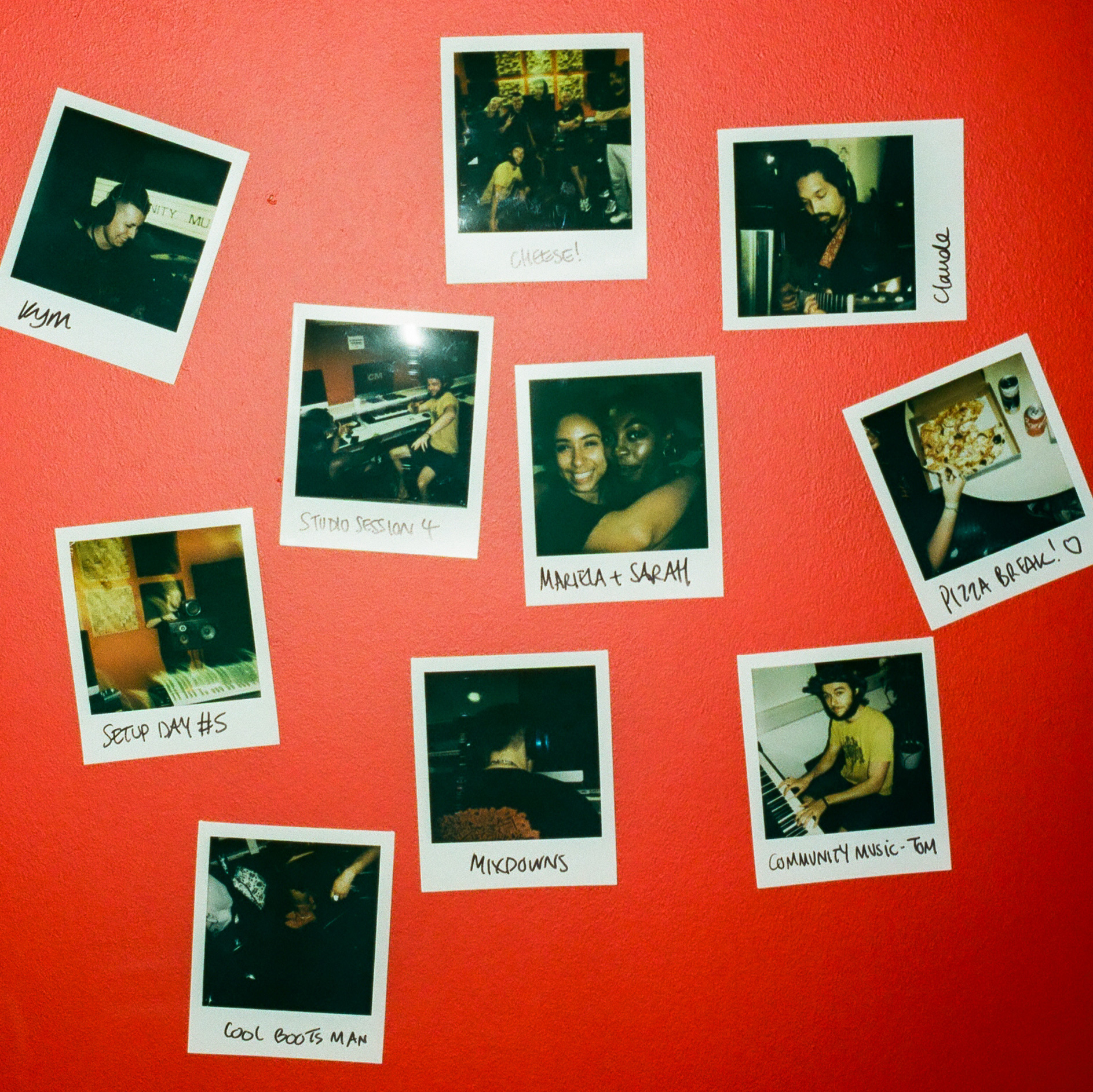 A selection of polaroid pictures of students in the studio stuck on a red wall.