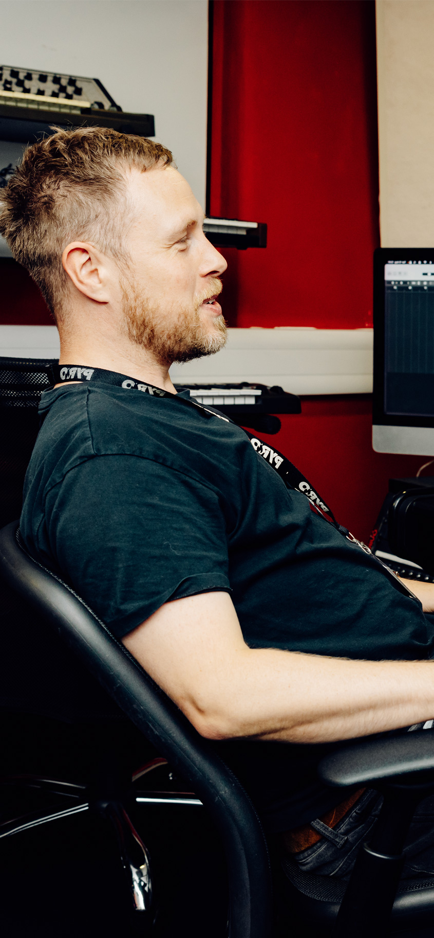 Male tutor leans back in studio chair.